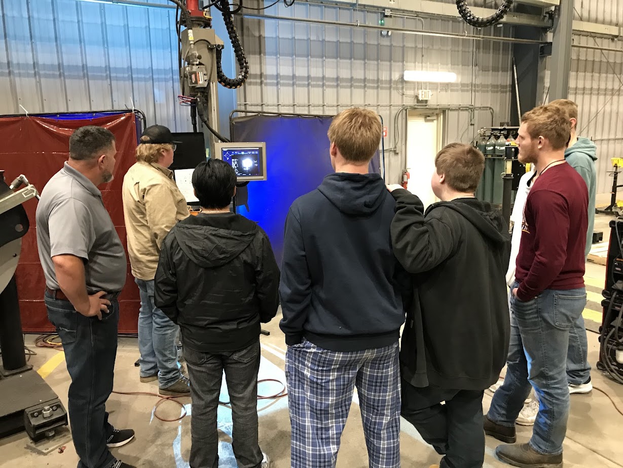 Students watching a welding robot at Fagen Fabrication